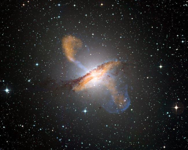 Colour composite image of Centaurus A, revealing the lobes and jets emanating from the active galaxy’s central black hole. This is a composite of images obtained with three instruments, operating at very different wavelengths. The 870-micron submillimetre