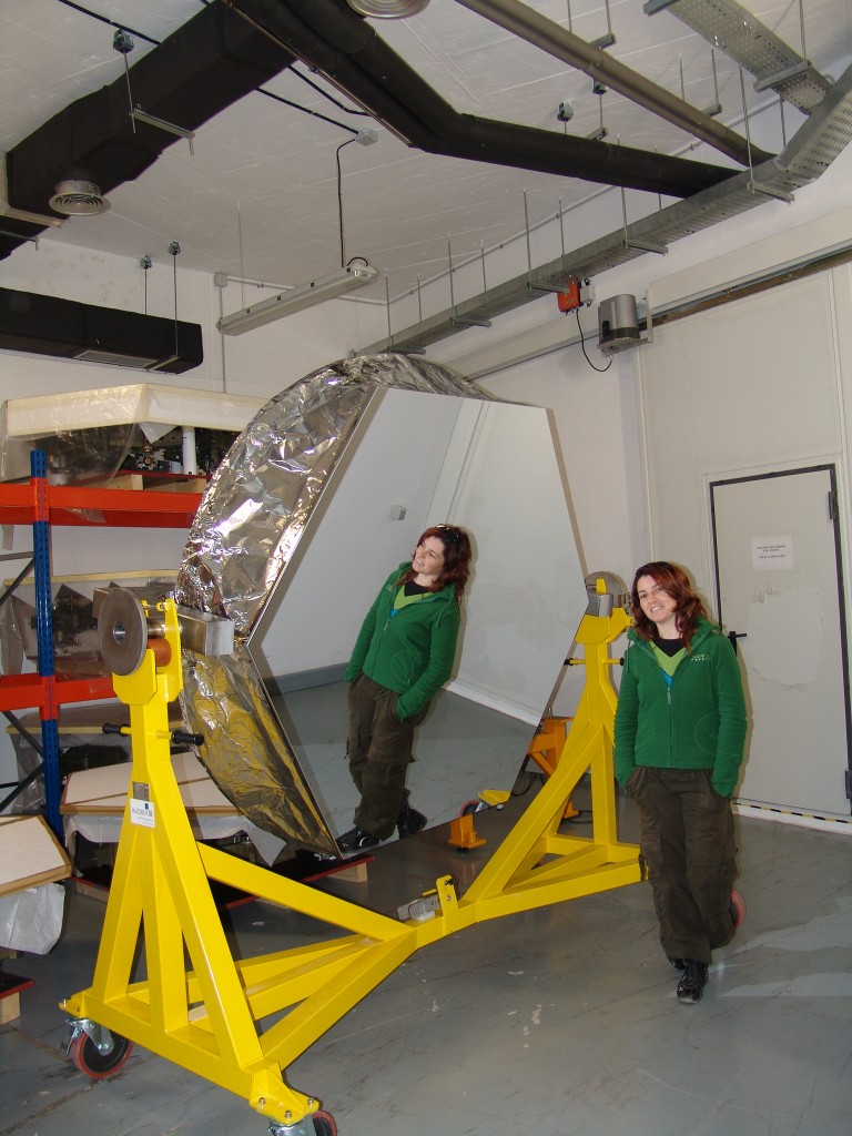 La autora del post frente a uno de los espejos del Gran Telescopio Canarias, en la sala de almacenaje de espejos cuando aún no habían sido instalados. Crédito: Gabriel Pérez, 2006.