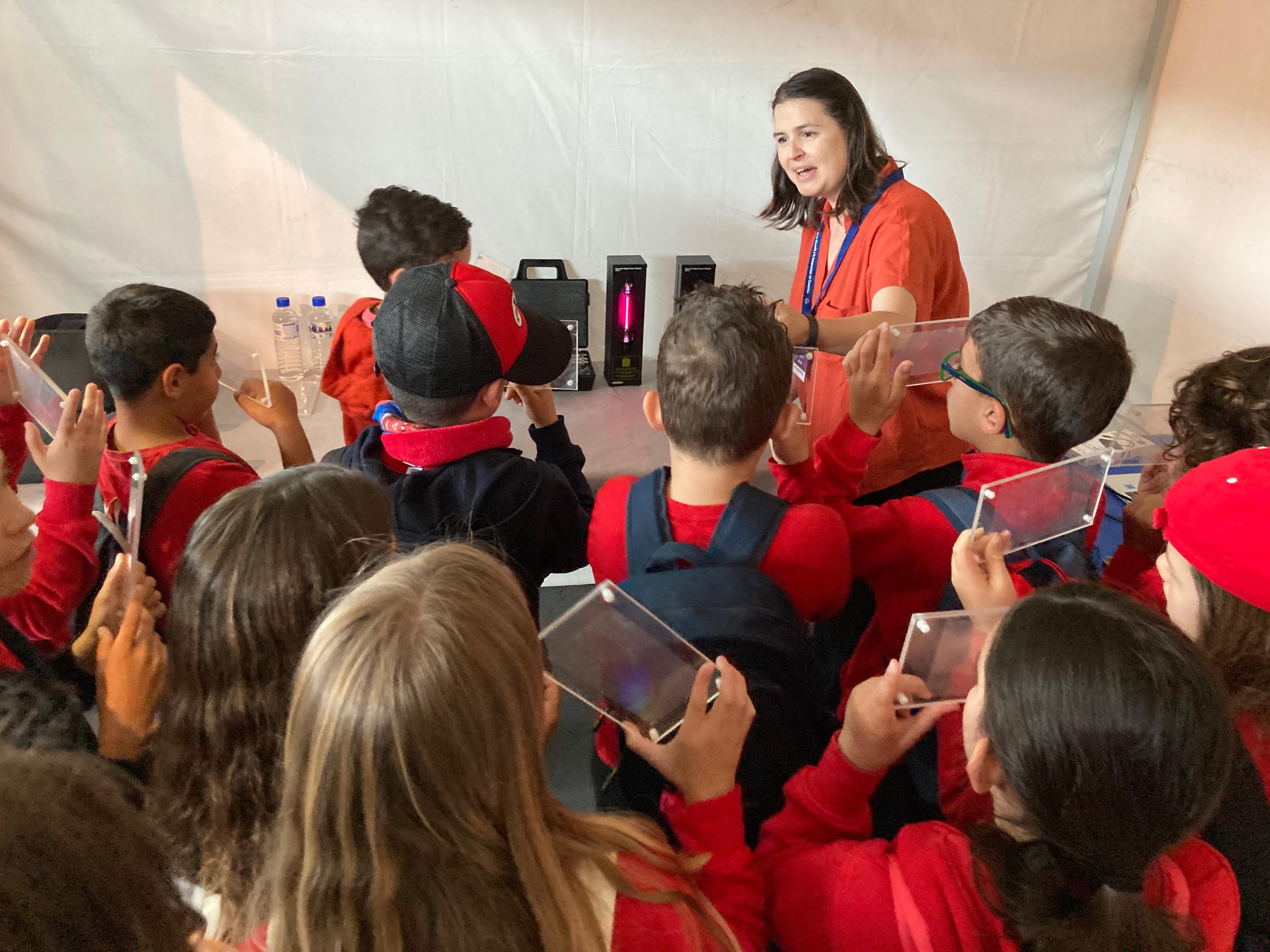 Estudiantes observan la luz emitida por diferentes gases con redes de difracción en el stand del IAc en la Miniferia de la Ciencia en La Palma
