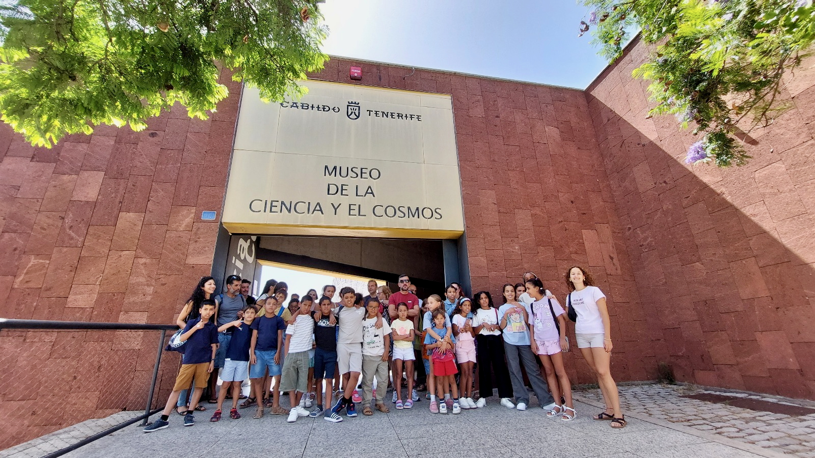 Grupo de escolares saharauis del programa “Vacaciones en Paz” y sus familias de acogida de Tenerife en la entrada del Museo de la Ciencia y el Cosmos