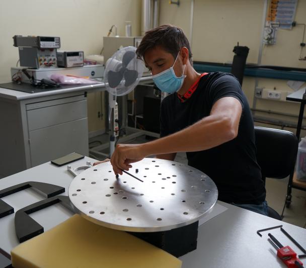 Imagen de Pablo de Chaves, ingeniero de IACTEC, ensamblando el útil de test para los ensayos de vibración del instrumento DRAGO en las instalaciones del Área de Ensayos del INTA (Instituto Nacional de Técnica Aeroespacial). Crédito: Alba Peláez (IAC).