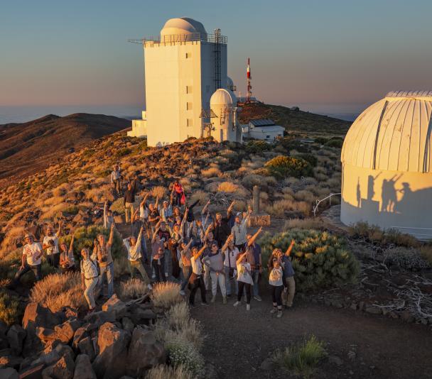 Asistentes al curso "Acércate al Cosmos" 2022 al atardecer con las torres solares al fondo