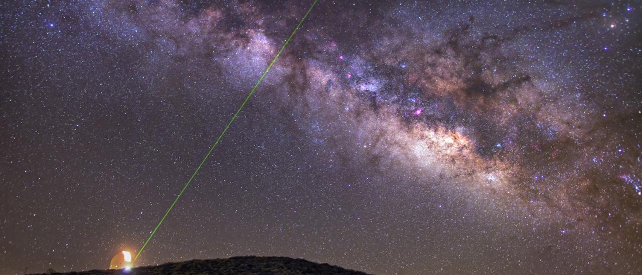 Imagen nocturna de la Vía Láctea y de la emisión de un láser verde desde la OGS durante pruebas de comunicaciones con La Palma. Autor D. López