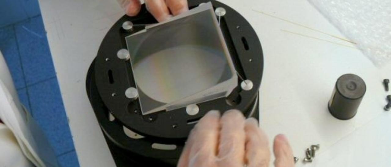 View of an engineer assembling a grism in the laboratory. Engineer placing a piece of glass in a metal cylinder