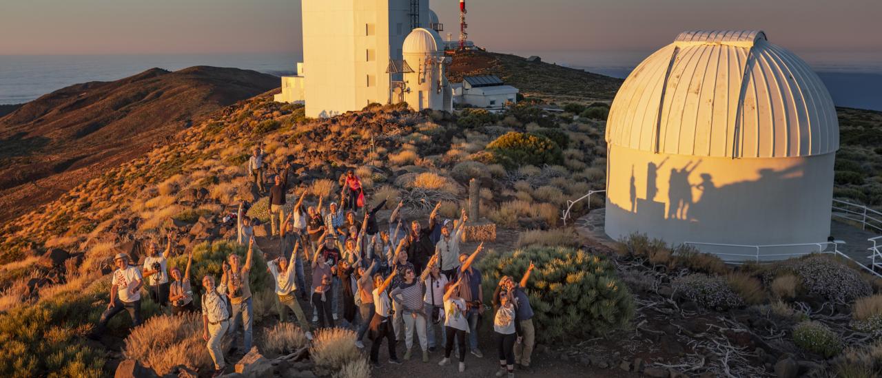 Asistentes al curso "Acércate al Cosmos" 2022 al atardecer con las torres solares al fondo