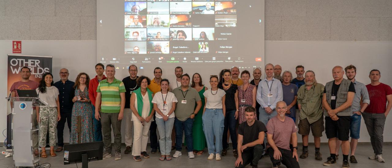 Foto de grupo con los ponentes, los participantes presenciales y los participantes en modo telemático