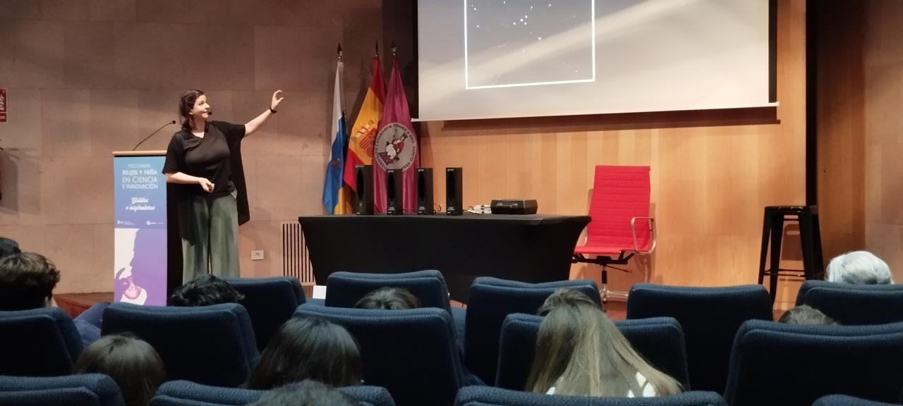La divulgadora señala al público un área del cielo que aparece en la pantalla