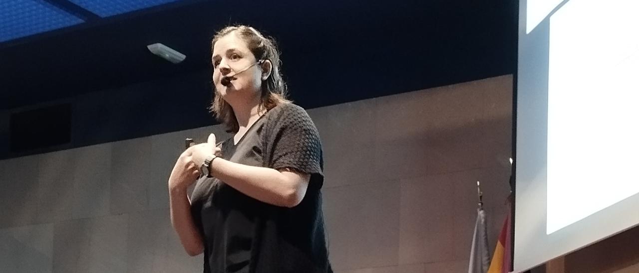 Una mujer habla sonriendo a un público que está fuera de la imagen