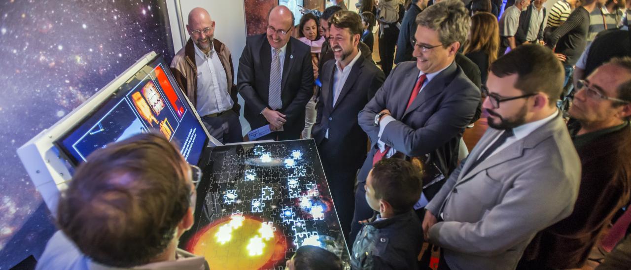 El director del IAC, Rafael Rebolo, el presidente del Cabildo de Tenerife, Carlos Alonso, el director de la ACIISI, Juan Ruiz Alzola, y el Director General de Cultura del Gobierno de Canarias, Xerach Gutiérrez Ortega, con los comisarios de la exposición "Luces del Universo" y público general en el módulo sobre "Hitos científicos del IAC".