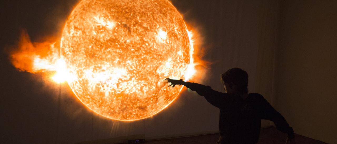 A child playing in front of the interactive module "Solar Immersion" in the "Lights of the Universe" exhibition. Credits: Daniel López/IAC. 