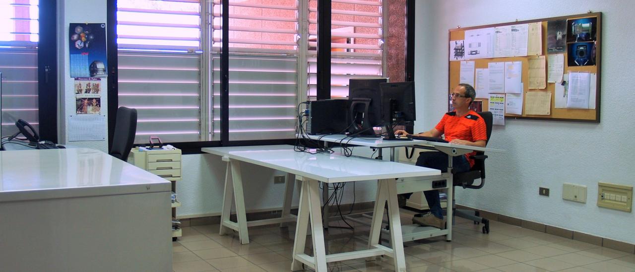 Partial view of the technical drawing workshop with a technician working in front of a desktop computer