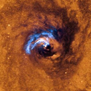 La imagen muestra el proceso de alimentación nuclear de un agujero negro en la galaxia NGC 1566 y cómo los filamentos de polvo que envuelven el núcleo activo quedan atrapados, girando alrededor del agujero negro hasta que son tragados por él. Crédito: ESO.
