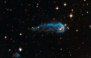 Protoestrella IRAS 20324+4057. El material extraído de la envoltura protoestelar es lo que vemos en la imagen con forma de cometa u oruga azul. La protoestrella en sí y la densa envoltura de polvo y gas que la rodea llamada cocoon (‘capullo’, en inglés) e 8232