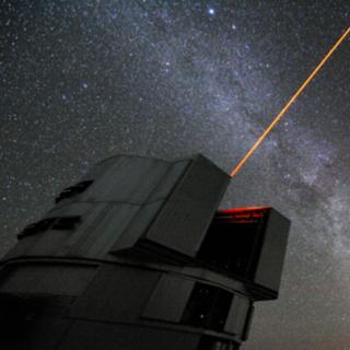 Un rayo láser lanzado desde el telescopio Yepun del VLT y en el fondo una vista majestuosa del cielo del sur, con el disco de la Vía Láctea cruzando la imagen y las Nubes de Magallanes en la parte superior derecha Una vista de nuestra galaxia, la Vía Láctea, con sus vecinos cercanos, las Nubes de Magallanes