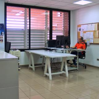 Partial view of the technical drawing workshop with a technician in a work station Partial view of the technical drawing workshop with a technician working in front of a desktop computer