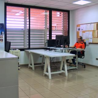 Partial view of the technical drawing workshop with a technician working in front of a desktop computer