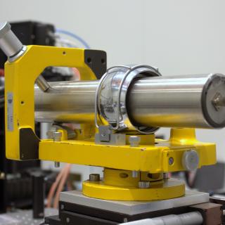 Detalle de un telescopio de alineado en un montaje en el laboratorio. Pequeño telescopio cilíndrico sobre una base metálica ajustable