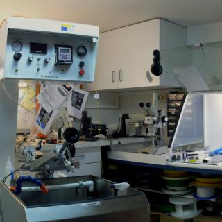 Vista panorámica del laboratorio de fibras ópticas. A la izquierda, máquina para colocar los materiales a pulir con mandos de control en la parte superior y a la derecha, mesas de trabajo con campanas extractoras de gases