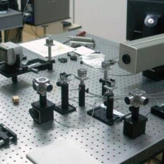 Vista del interferómetro en el laboratorio. Pequeños dispositivos ópticos y electrónicos alineados en forma de cruz en una mesa de laboratorio