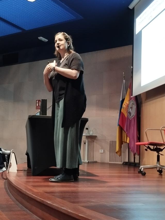 Una mujer habla sonriendo a un público que está fuera de la imagen